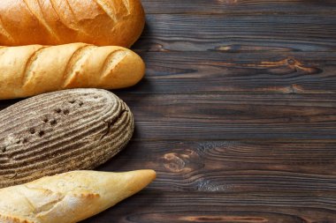 Fırın arka plan, siyah ahşap zemin üzerinde ekmek ürün yelpazesine sahip. Kopya alanı ile Üstten Görünüm