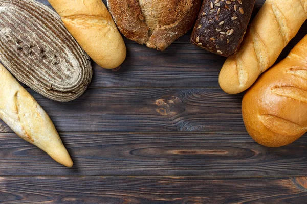 Bakery background, bread assortment on black wooden backdrop. Top view with copy space — Stock Photo, Image