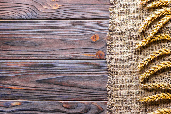 Wheat ears border on old burlap on wooden background