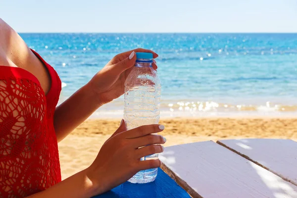 Frau öffnet am Strand eine Flasche Wasser — Stockfoto