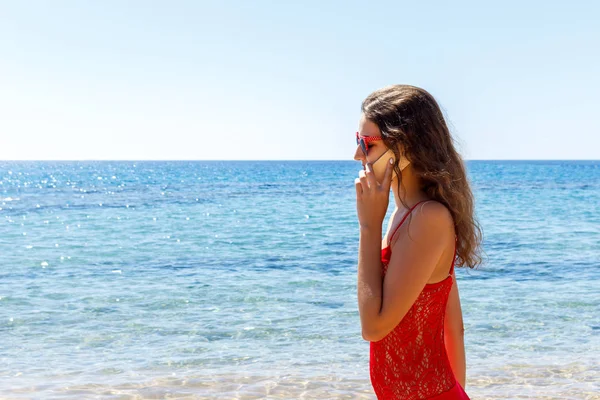Mladá usměvavá žena mluvila telefonicky na pláži — Stock fotografie