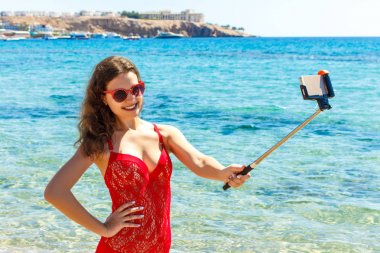 Kız sahilde bir akıllı telefon ile mayo. Eğlenceli alarak kız plajda selfie