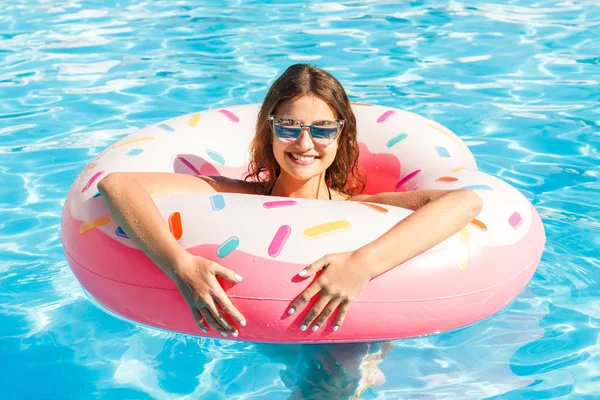 Piękna młoda kobieta z różowe koło relaksujący w niebieski basen — Zdjęcie stockowe