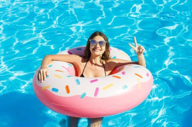 Yüzme havuzunda biri siyah bikini ve güneş gözlüğü