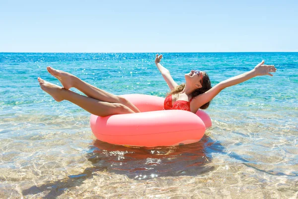 Chica sonriente feliz disfruta flotando en la rosquilla inflable en el mar. tiempo de vacaciones —  Fotos de Stock