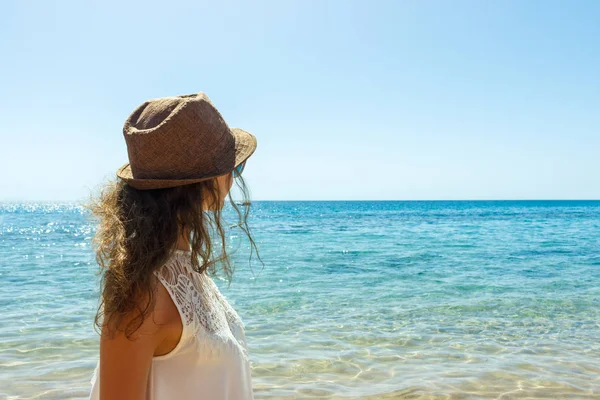 Osamělá dívka s větrem v jejím pozadí moře vlasy při pohledu na klidné moře — Stock fotografie