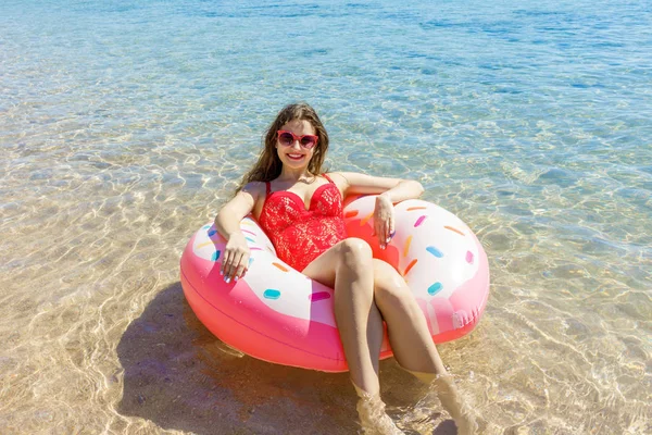 Красивая молодая женщина с надувным пончиком в море — стоковое фото