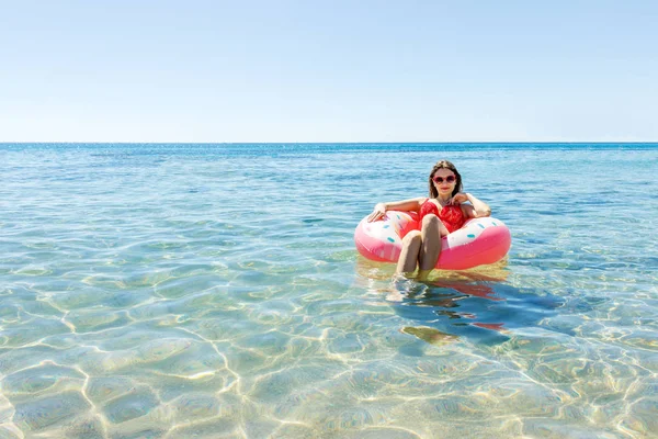 Mulher nova bonita com donut inflável no mar — Fotografia de Stock