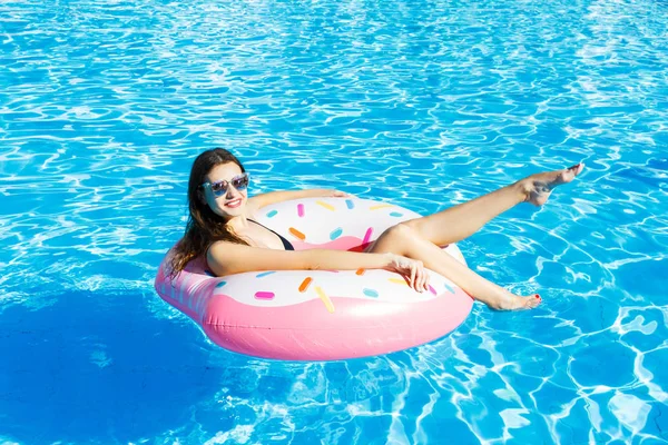 Chica divirtiéndose y riendo en un anillo inflable de color rosa. Mujer en piscina —  Fotos de Stock