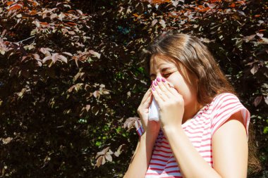 Genç Kız parkta çiçek açan ağaçlar arasında peçete ile hapşırma. Anti kavramı