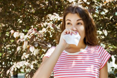 Genç kız onun burun üfleme. Anti sonbahar Park ile genç kız