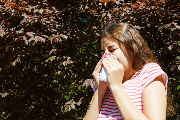 Genç Kız parkta çiçek açan ağaçlar arasında peçete ile hapşırma. Anti kavramı