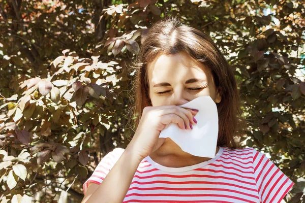 Genç kız alerjisi sonbahar Park. Hapşırma kız peçeteye burnunu darbeler