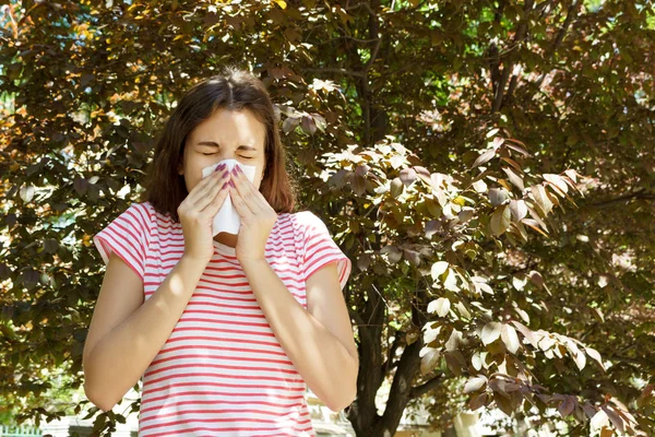 Ung söt flicka blåser näsan framför trädet. Våren allergi koncept — Stockfoto