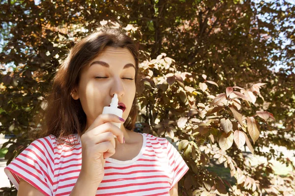 Ung vacker kvinna använder nässpray i parken — Stockfoto