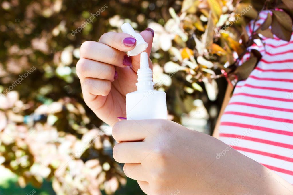 female hand holding a bottle nasal spray in the park