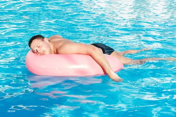 Vista dall'alto del giovane ragazzo ubriaco nuotare con cerchio rosa in piscina. ragazzo ubriaco in vacanza in hotel — Foto Stock