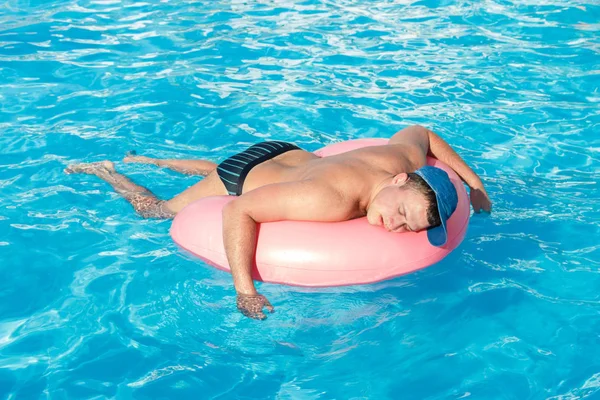 Borracho descansando chico en el círculo inflable en la piscina del hotel —  Fotos de Stock