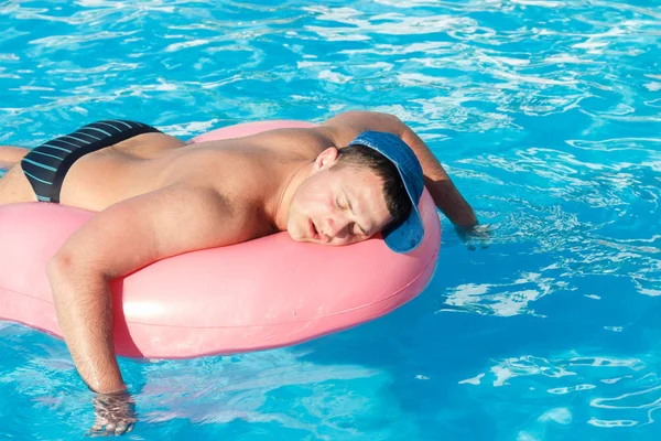 Vista superior de un joven borracho nadando con un círculo rosa en la piscina. borracho chico de vacaciones en el hotel —  Fotos de Stock