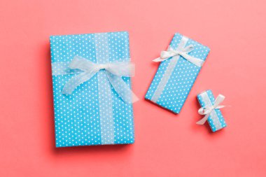 Yaşayan mercan arka planında beyaz kurdeleli kağıtlara sarılmış Noel veya diğer tatil hediyeleri. Hediye kutusu, hediye dekorasyonu renkli masa, üst görünüm