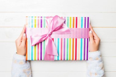 Beyaz ahşap masa zemininde renkli kurdeleli hediye paketi, üst görünüm kopya alanı