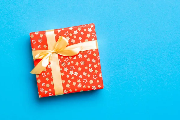 Envuelto Navidad u otro regalo hecho a mano de vacaciones en papel con cinta de oro sobre fondo azul. Caja de regalo, decoración de regalo en mesa de colores, vista superior con espacio para copiar —  Fotos de Stock