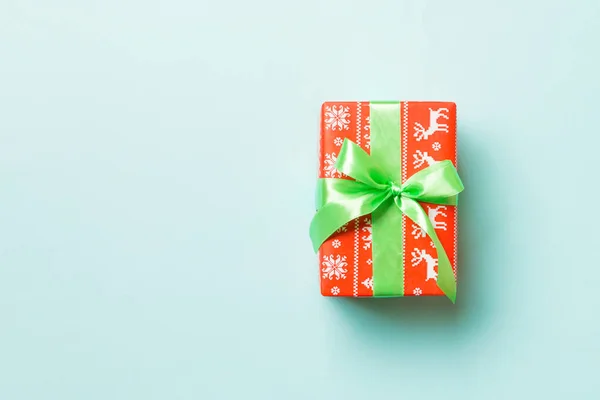 Dárkový box se zeleným lukem na Vánoce nebo na Nový rok na modrém pozadí, horní pohled s kopírovacím prostorem — Stock fotografie