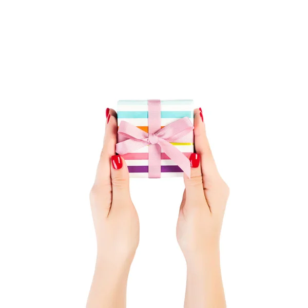 Vrouw handen geven verpakt Kerstmis of andere vakantie met de hand gemaakt in gekleurd papier met roze lint. Geïsoleerd op witte achtergrond, bovenaanzicht. dankzegging Geschenkdoos concept — Stockfoto