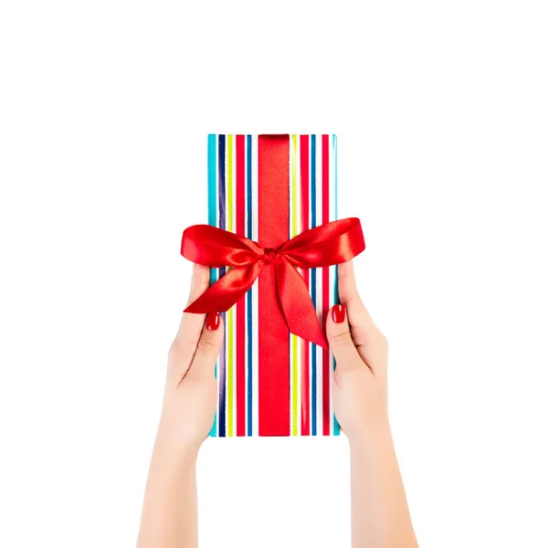 女性の手は赤いリボンで着色された紙に包まれたクリスマスや他の休日の手作りプレゼントを与える。白い背景に、上部のビューに隔離された。感謝祭のギフトボックスコンセプト — ストック写真