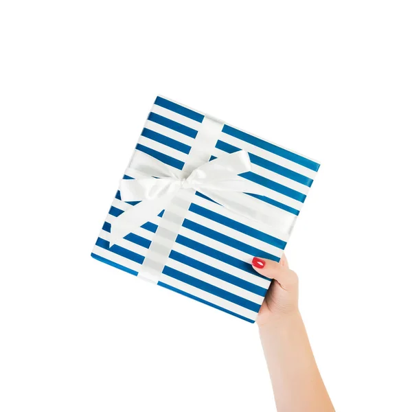 Vrouw handen geven verpakt Kerstmis of andere vakantie met de hand gemaakt in blauw papier met wit lint. Geïsoleerd op witte achtergrond, bovenaanzicht. dankzegging Geschenkdoos concept — Stockfoto