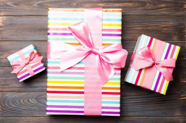 Koyu ahşap masanın üzerinde renkli bir fiyonk olan güzel bir hediye kutusu. Tasarımınız için fotokopi alanı olan üst görünüm. Noel konsepti