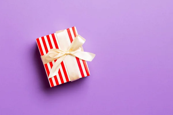 Zawinięte Boże Narodzenie lub inne świąteczne ręcznie robione prezenty w papier z żółtą wstążką na fioletowym tle. Prezentowane pudełko, dekoracja prezentu na kolorowym stole, widok z góry z miejsca na ksero — Zdjęcie stockowe