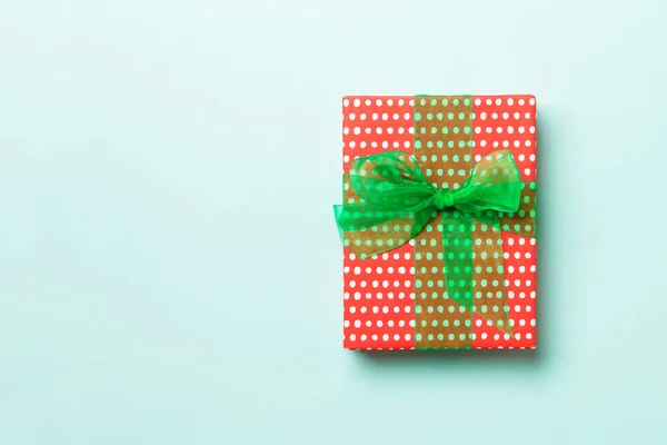青い背景に緑のリボンで紙にクリスマスや他の休日の手作りプレゼントを包んだ。プレゼントボックス、カラーテーブルのギフトの装飾、コピースペース付きのトップビュー — ストック写真