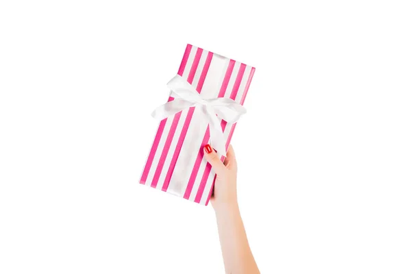 Vrouw handen geven verpakt Kerstmis of andere vakantie met de hand gemaakt in roze papier met wit lint. Geïsoleerd op witte achtergrond, bovenaanzicht. dankzegging Geschenkdoos concept — Stockfoto