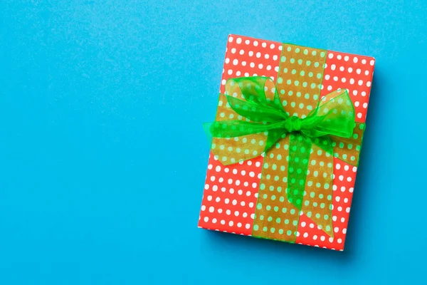 Zabalené vánoční nebo jiné sváteční ručně vyráběné dárek v papíru se zelenou stuhou na modrém pozadí. Dárek box, dekorace dárku na barevném stole, horní pohled s kopírovacím prostorem — Stock fotografie