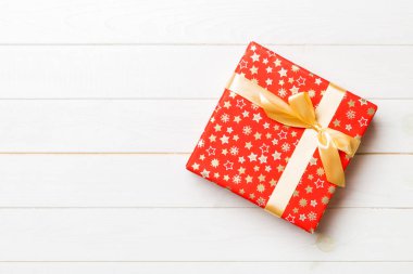 Beyaz ahşap masanın üzerinde renkli bir fiyonk olan güzel bir hediye kutusu. Tasarımınız için fotokopi alanı olan en iyi görünüm pankartı