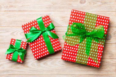 Turuncu ahşap masanın üzerinde renkli bir fiyonk olan güzel bir hediye kutusu. Tasarımınız için fotokopi alanı olan üst görünüm. Noel konsepti