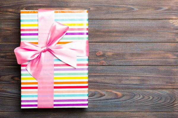 Papier-Geschenkbox mit farbigem Band auf dunklem Holz Hintergrund. Ansicht von oben mit Kopierraum Weihnachtsferien-Konzept — Stockfoto