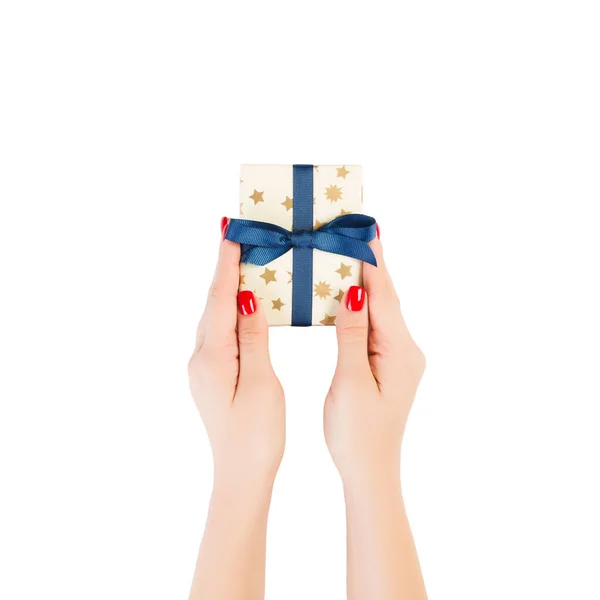 Woman hands give wrapped Christmas or other holiday handmade present in gold paper with blue ribbon. Isolated on white background, top view. thanksgiving Gift box concept — 스톡 사진