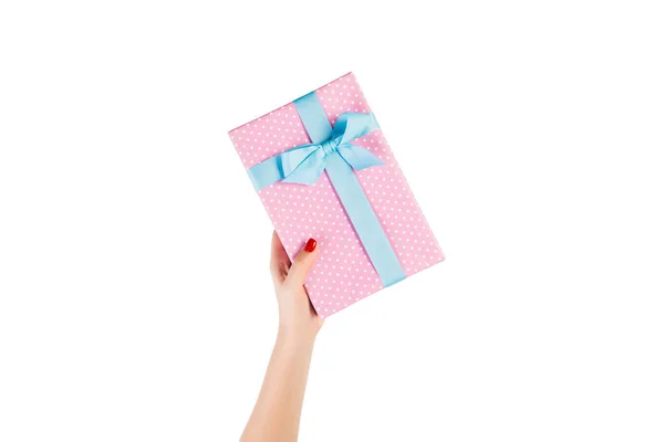 Vrouw handen geven verpakt Kerstmis of andere vakantie met de hand gemaakt in roze papier met blauw lint. Geïsoleerd op witte achtergrond, bovenaanzicht. dankzegging Geschenkdoos concept — Stockfoto