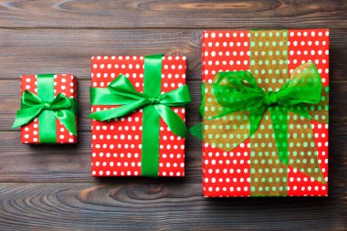 Koyu ahşap masanın üzerinde renkli bir fiyonk olan güzel bir hediye kutusu.. 