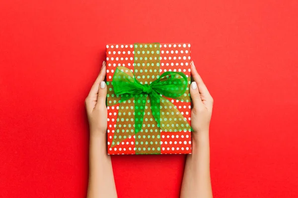 Las manos de la hembra sosteniendo caja de regalo a rayas con cinta de color en r —  Fotos de Stock