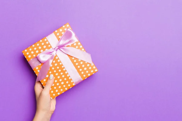 Flat lay de mãos de mulher segurando presente embrulhado e decorado com — Fotografia de Stock