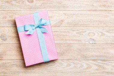 Sarı ahşap masanın üzerinde renkli bir fiyonk olan güzel bir hediye kutusu. Tasarımınız için fotokopi alanı olan en iyi görünüm pankartı