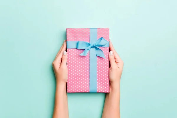 女人的手送给包装好的圣诞节或其他用彩纸手工制作的节日礼物。礼物盒，蓝色桌子上的礼物装饰，顶部有复制空间 — 图库照片