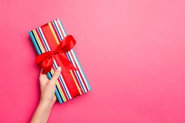 Manos de niña sosteniendo caja de regalo de papel artesanal con como regalo para Navidad u otras vacaciones sobre fondo rosa, vista superior con sppace de copia —  Fotos de Stock