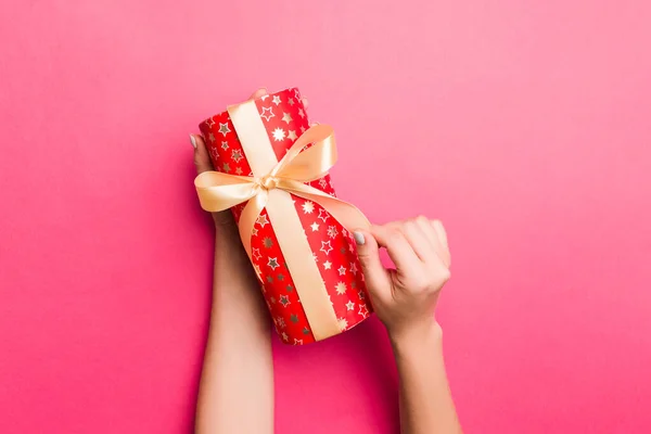 Lány kéz tartja kézműves papír ajándék doboz ajándékba karácsonyra vagy más ünnep rózsaszín háttér, felső nézet másolat sppace — Stock Fotó