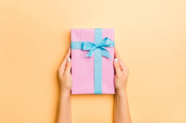 Hediye paketlenmiş ve süslenmiş bir kadın eli uzanıyor. 