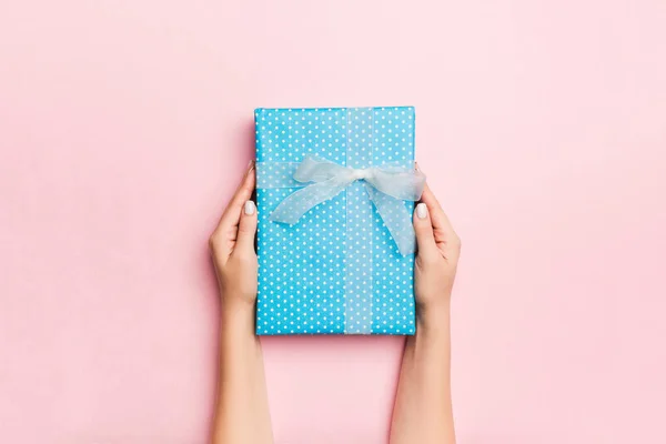 Mãos femininas segurando caixa de presente listrada com fita colorida em l — Fotografia de Stock