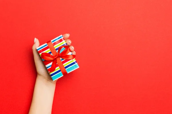 Las manos de la hembra sosteniendo caja de regalo a rayas con cinta de color en r —  Fotos de Stock